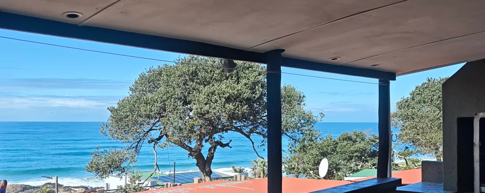 The sea from the covered stoep, framed by a milkwood