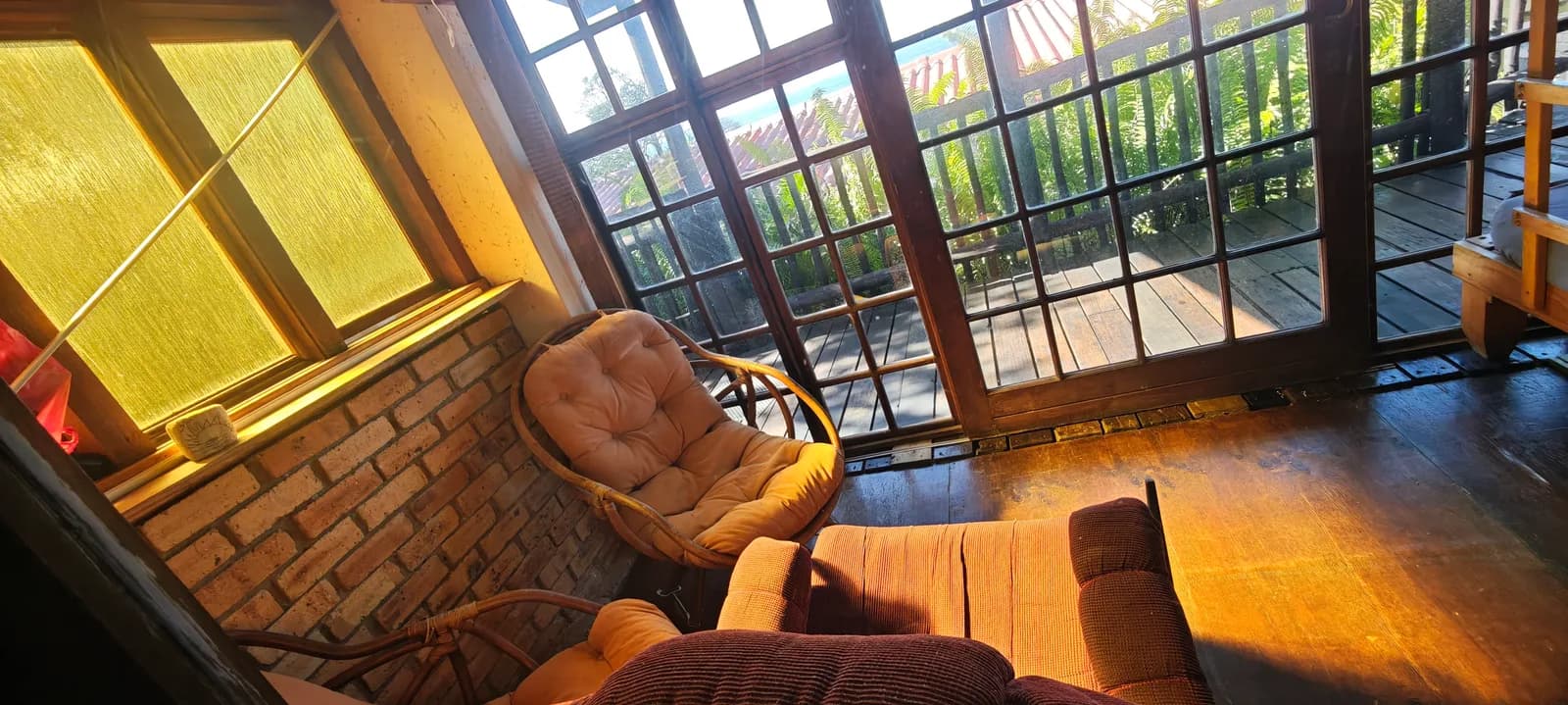 Enclosed sunroom with cane chairs and a wooden deck